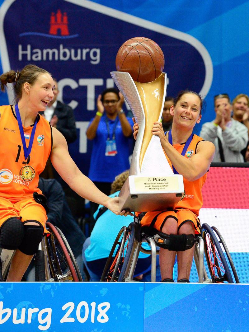 female wheelchair basketballer Carina de Rooij lifts up the trophy