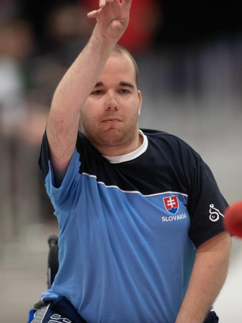 Male boccia player throws red ball