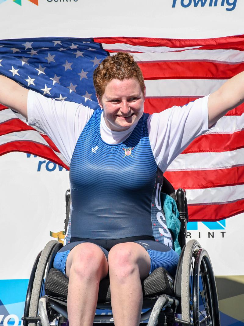 female Para rower Hallie Smith smiling and holding up a USA flag