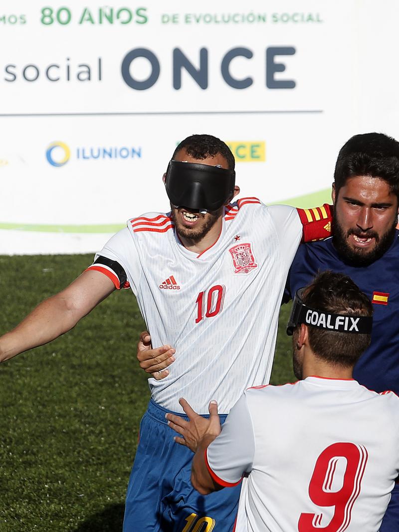 three male blind footballers including two from Spain battle for the ball