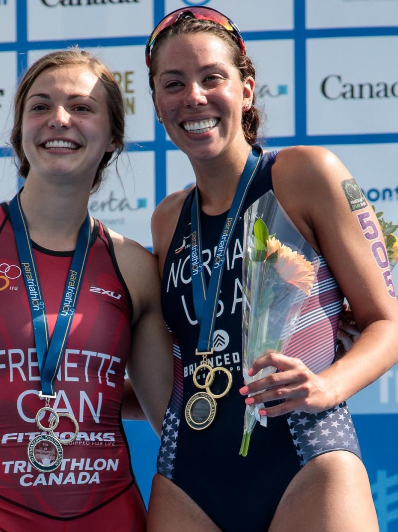 two female Para triathletes including Kamylle Frenette hugging on the podium