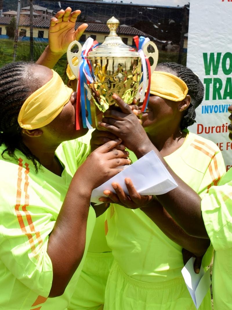 four female blind footballers kissing a trophy