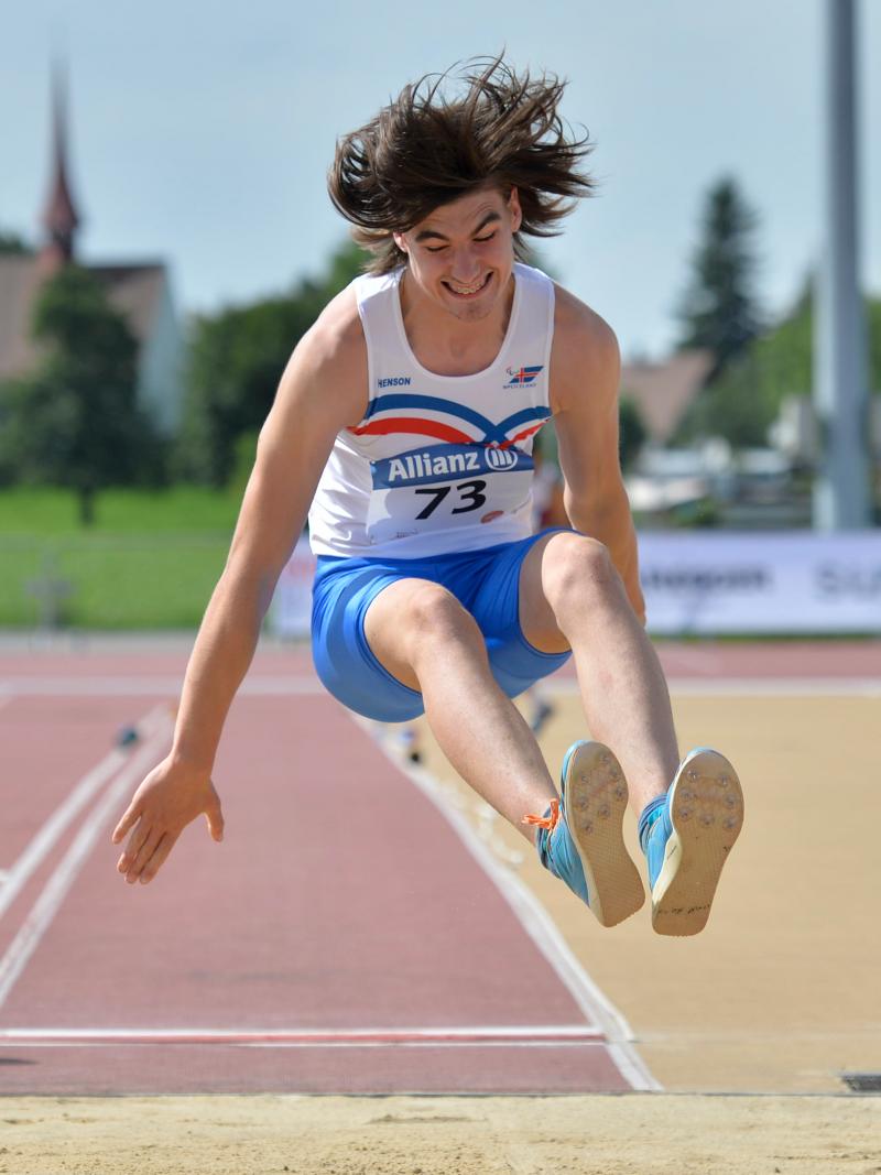 a male Para athlete jumps into a long jump sandpit