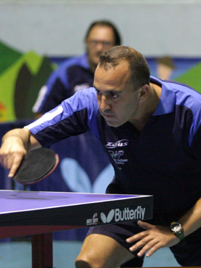 a male intellectually impaired table tennis player plays a backhand across the table