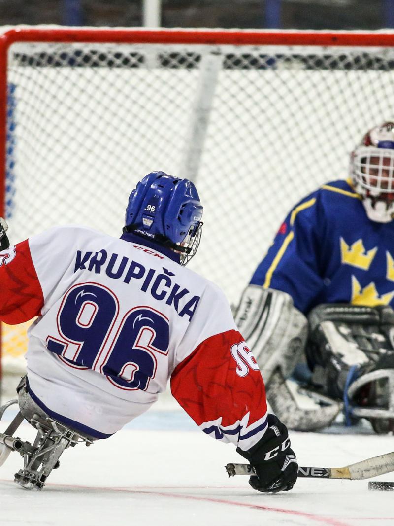 A Para ice hockey player taking a shot in front of the opponent's goal