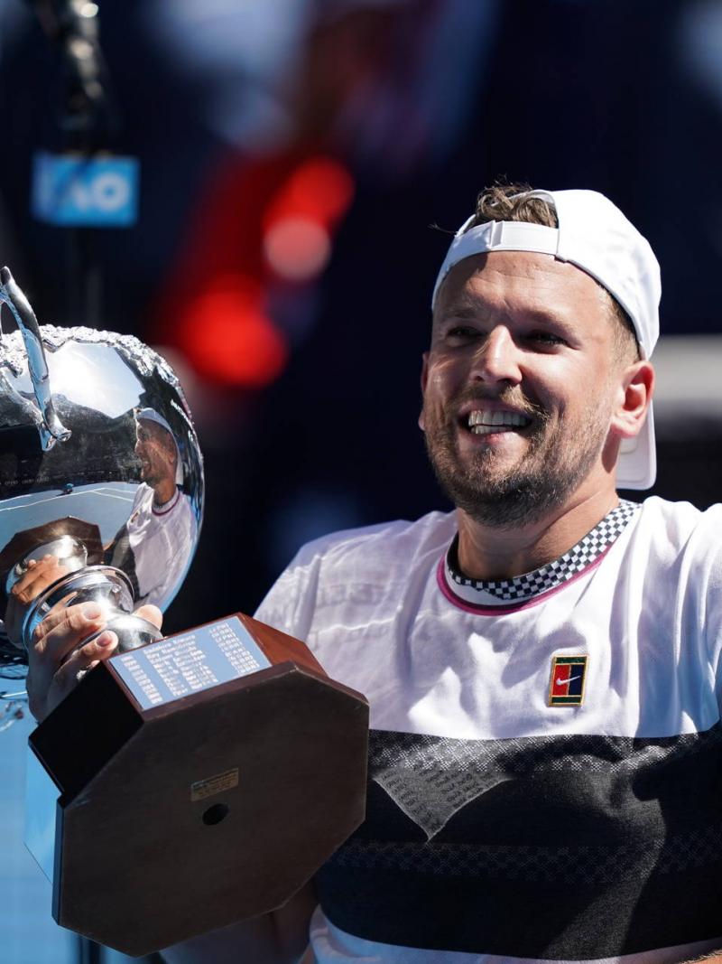 male wheelchair tennis player Dylan Alcott holds up a silver trophy and smiles