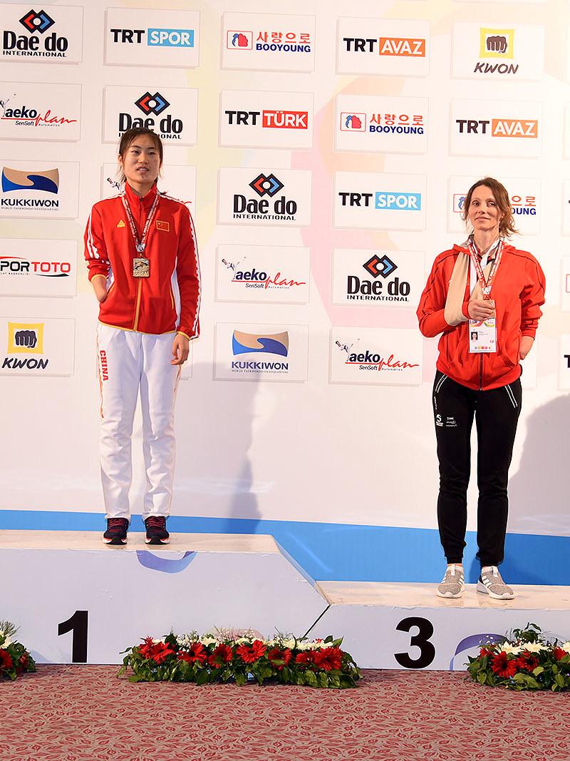 four female taekowondo fighters on the podium with Yujie Li on the top step