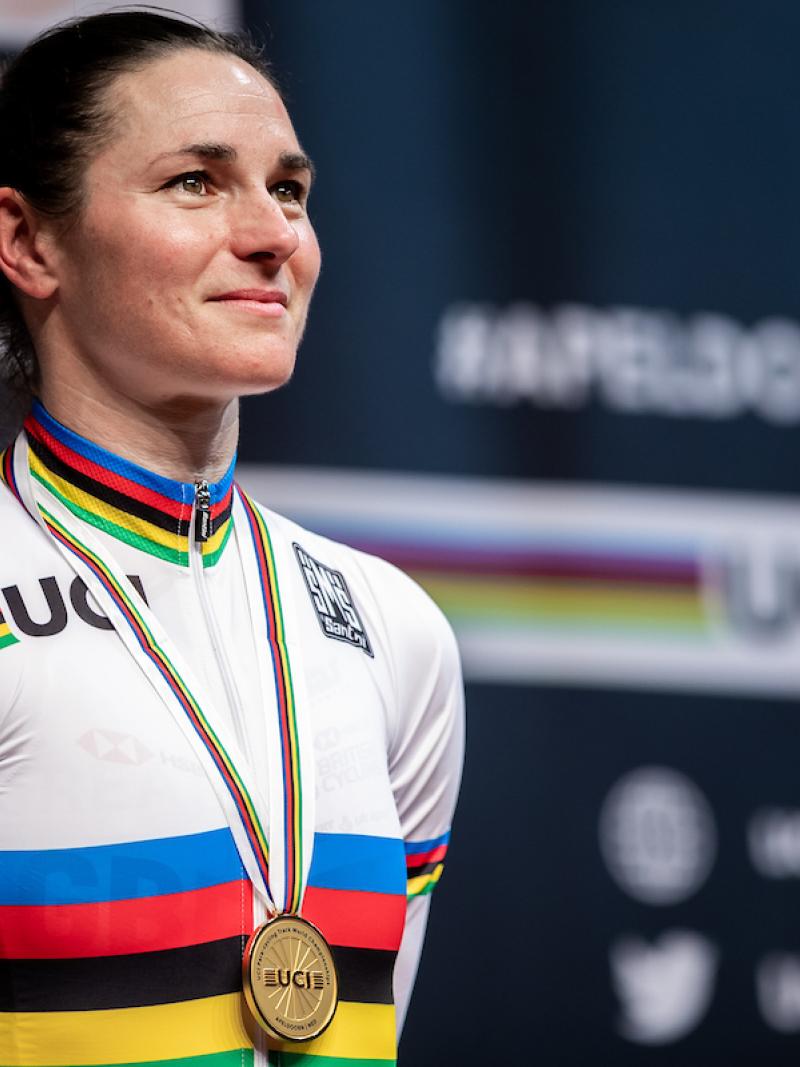 female Para cyclist Sarah Storey stands on the podium with a gold medal around her neck