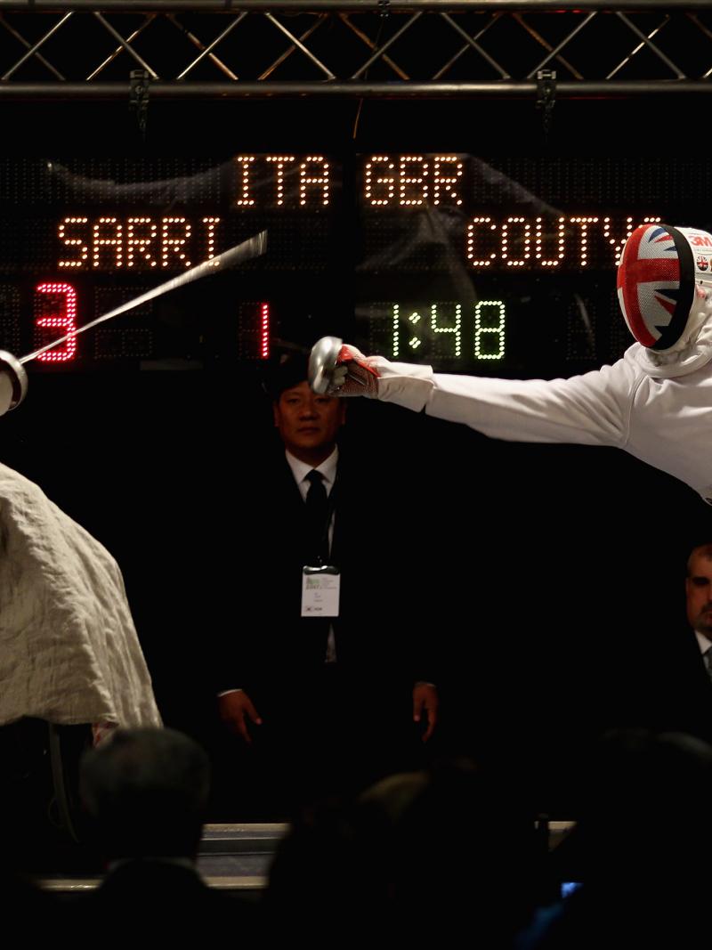 male wheelchair fencer Alessio Sarri leans back to avoid another fencer's foil