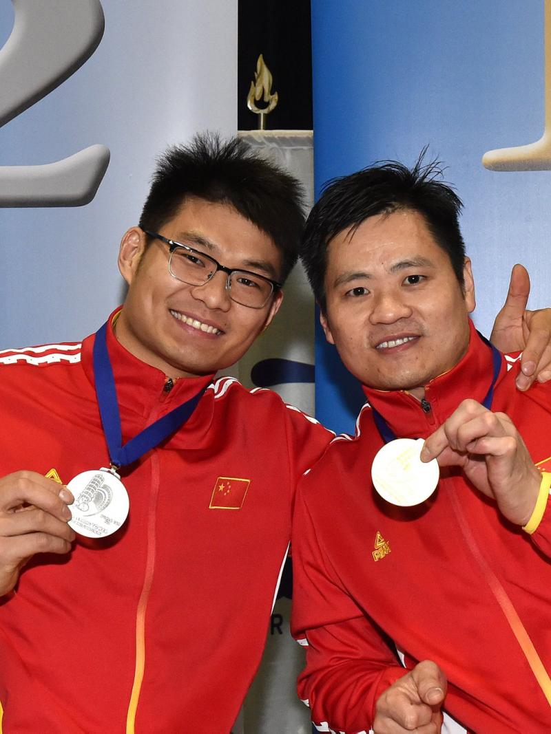 male wheelchair fencers Hu Daoliang and Feng Yanke hold up their medals and smile