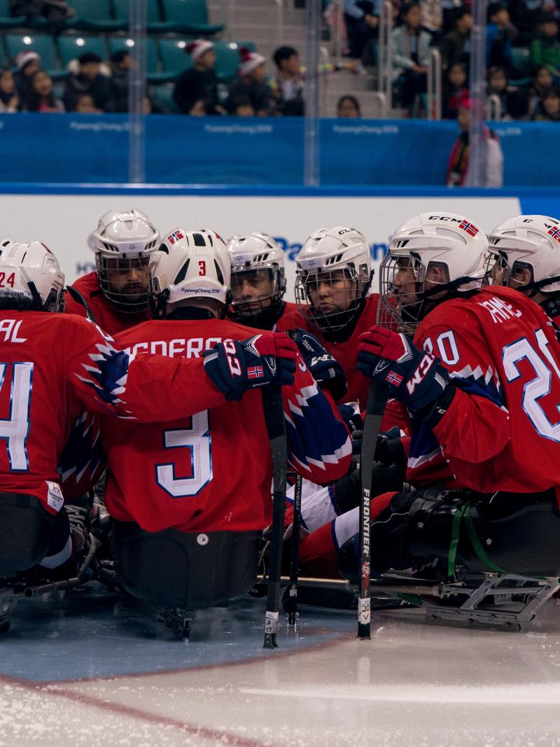 Norwegian Para ice hockey players huddle on an ice rink