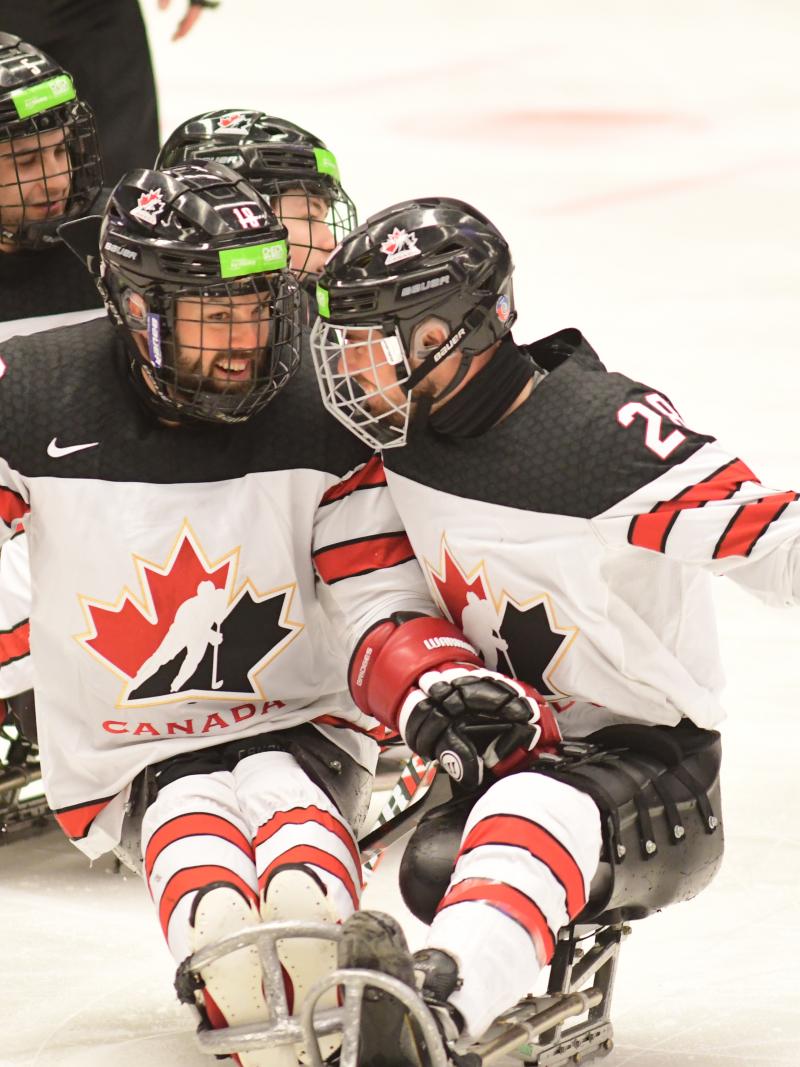 male Para ice hockey player Antoine Lehoux celebrates with another player hugging on the ice