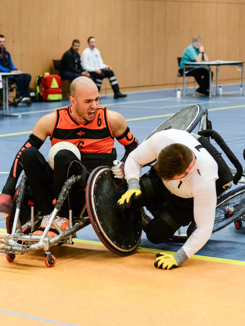Two men in wheelchair chairs collide playing wheelchair rugby