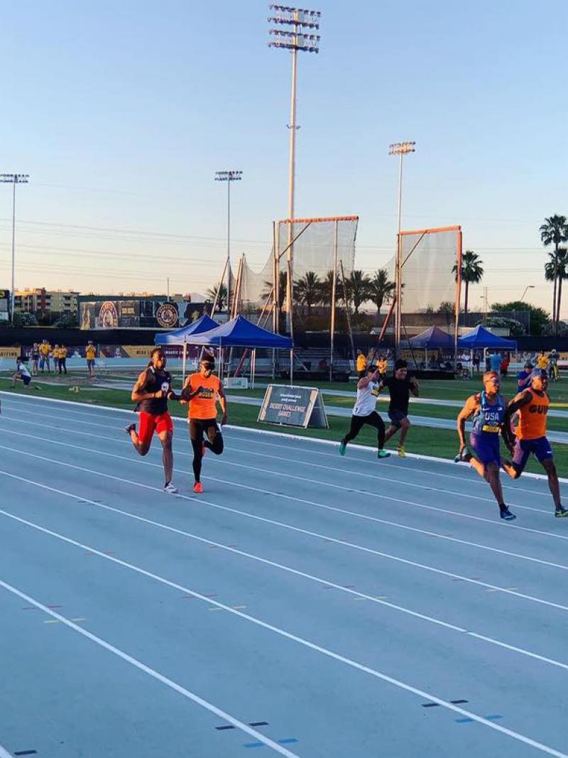 Four male vision impaired runners and thir guides racing on a track