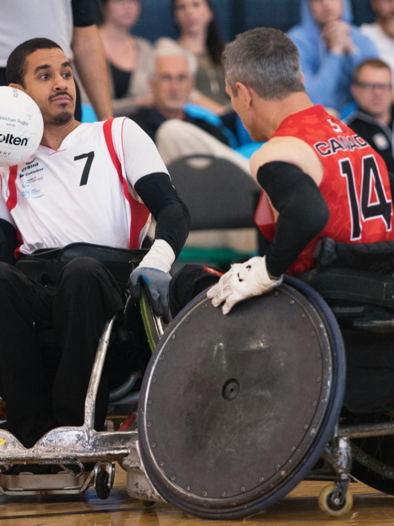 Swiss man in wheelchair rugby protects the ball against his opponent