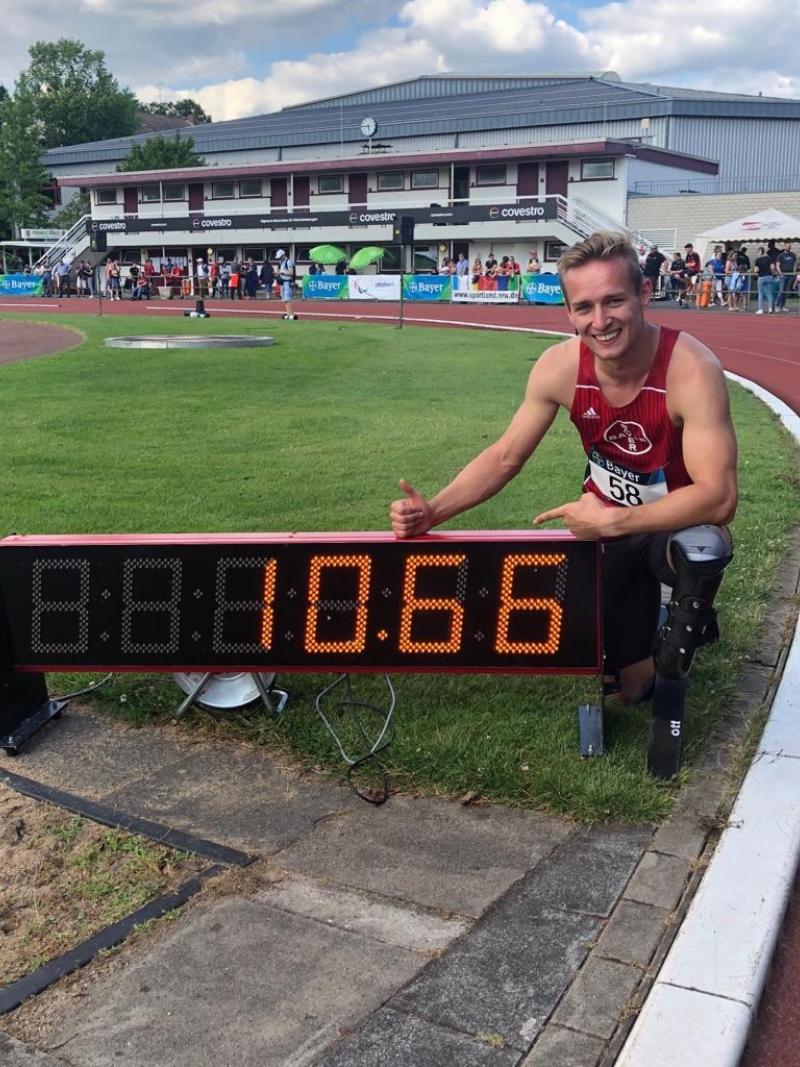 German male sprinter poses next to a clock that says 10.66