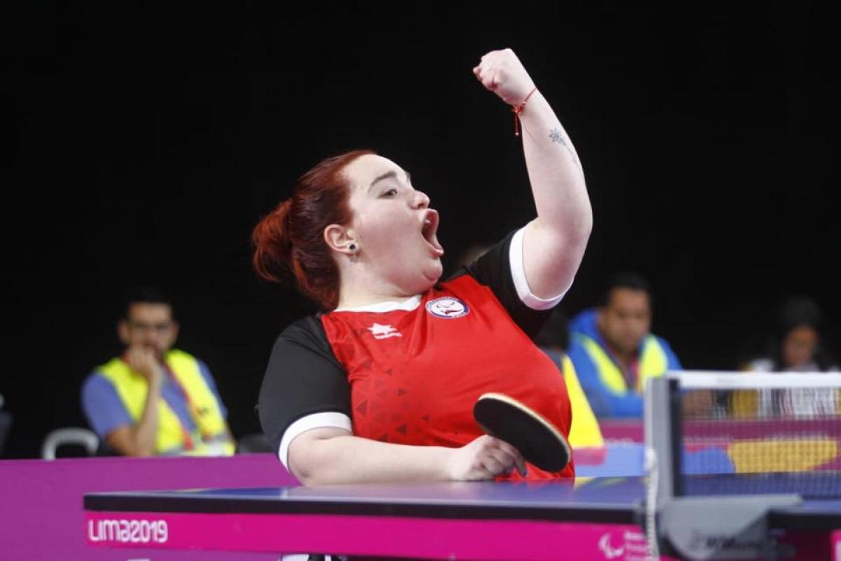 a female wheelchair table tennis player punches the air in victory