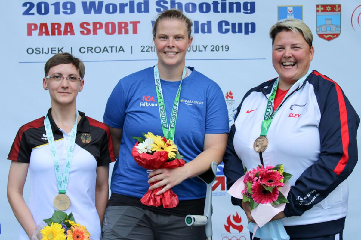 Three female shooting Para sport athletes podium winners pose