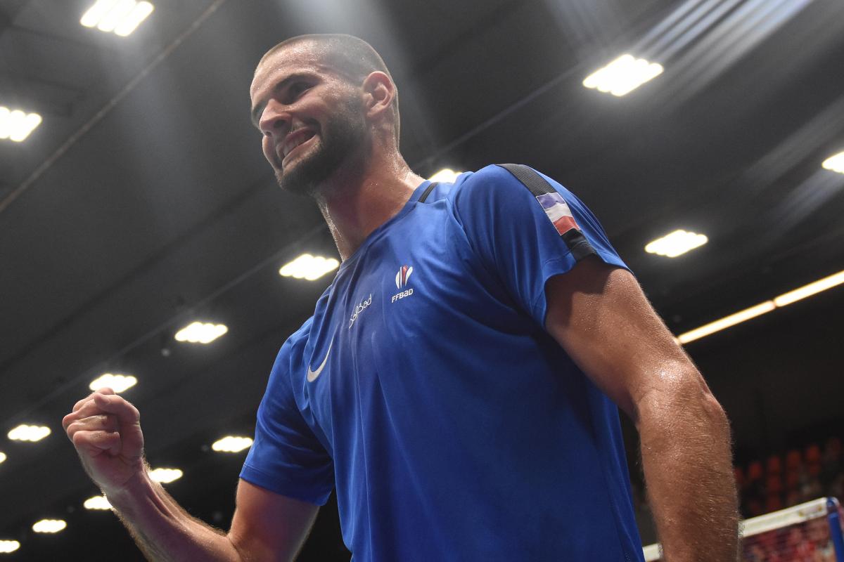 French male badminton player clutches fist smiling