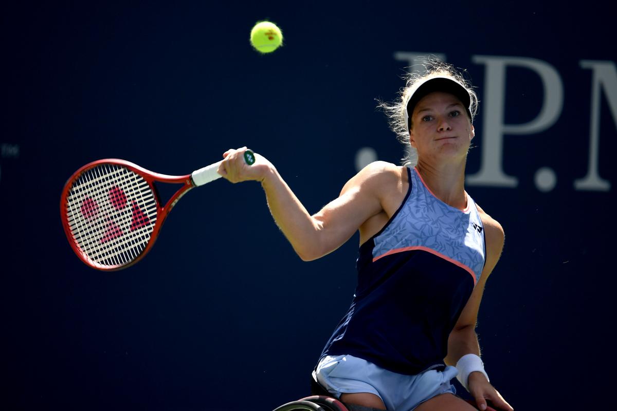 a female wheelchair tennis player hits a forehand