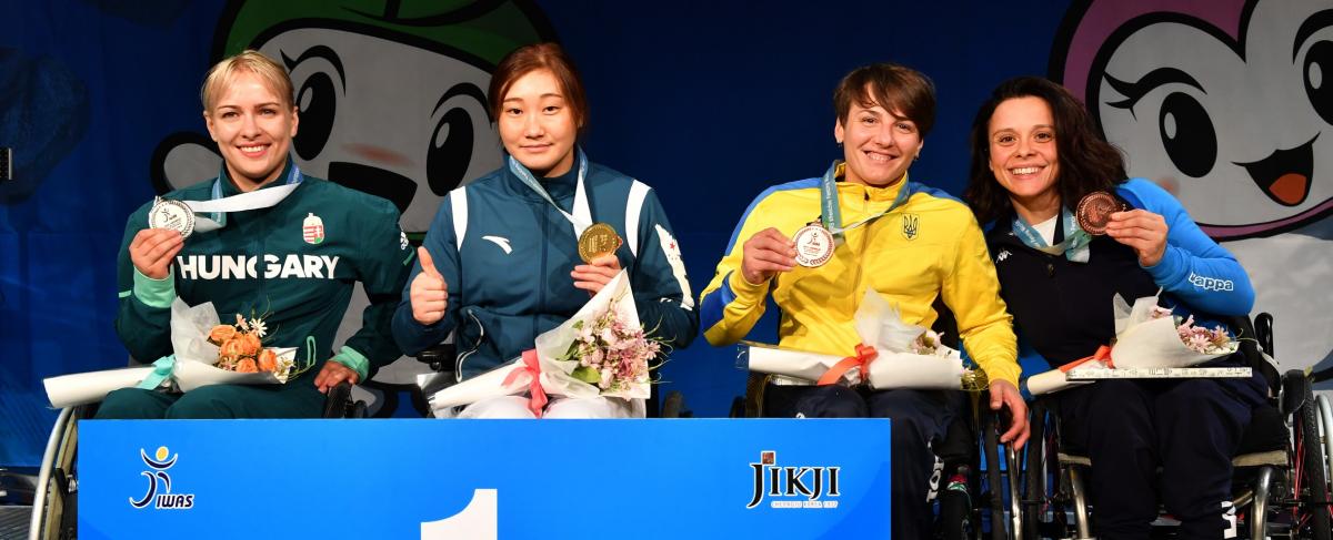 Four female wheelchair fencers holding up their medals