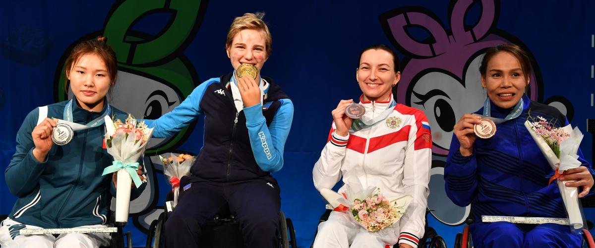 Four women pose on the podium holding their medals