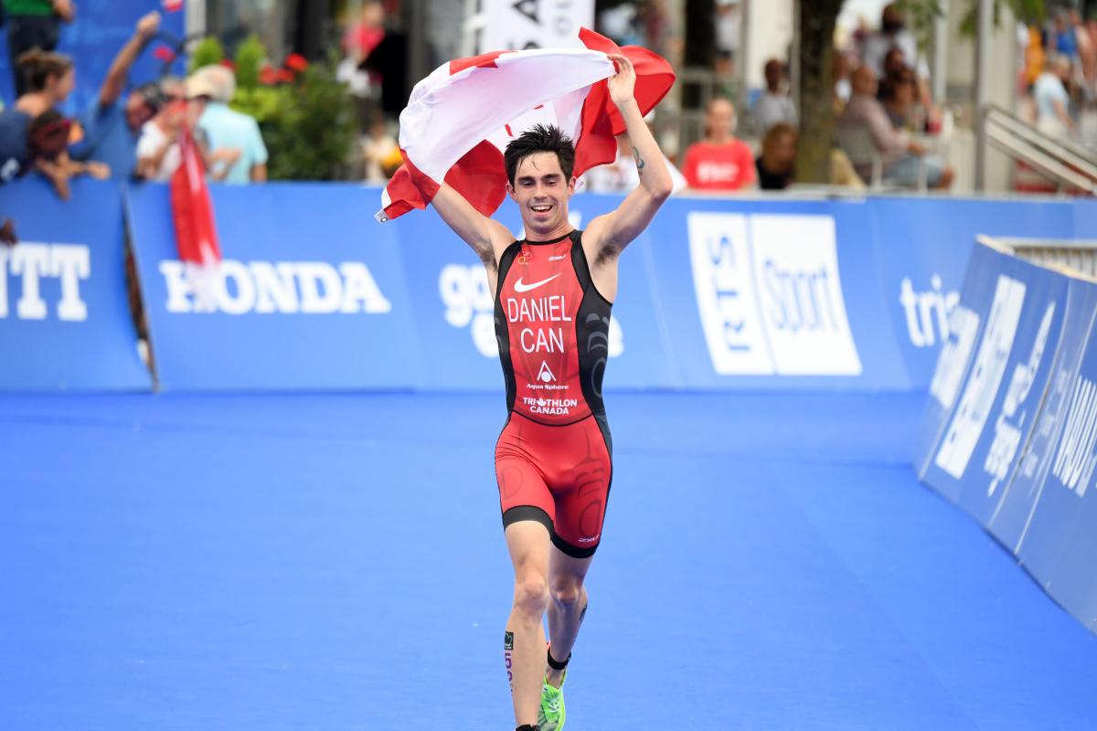 Male triathlete with arm disability holds Canadian flag