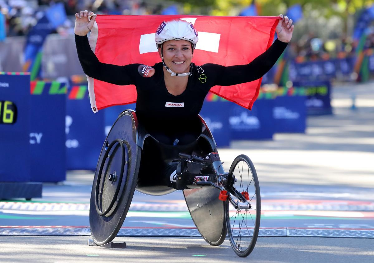 Manuela Schär holds the Swiss flag and smiles to the camera