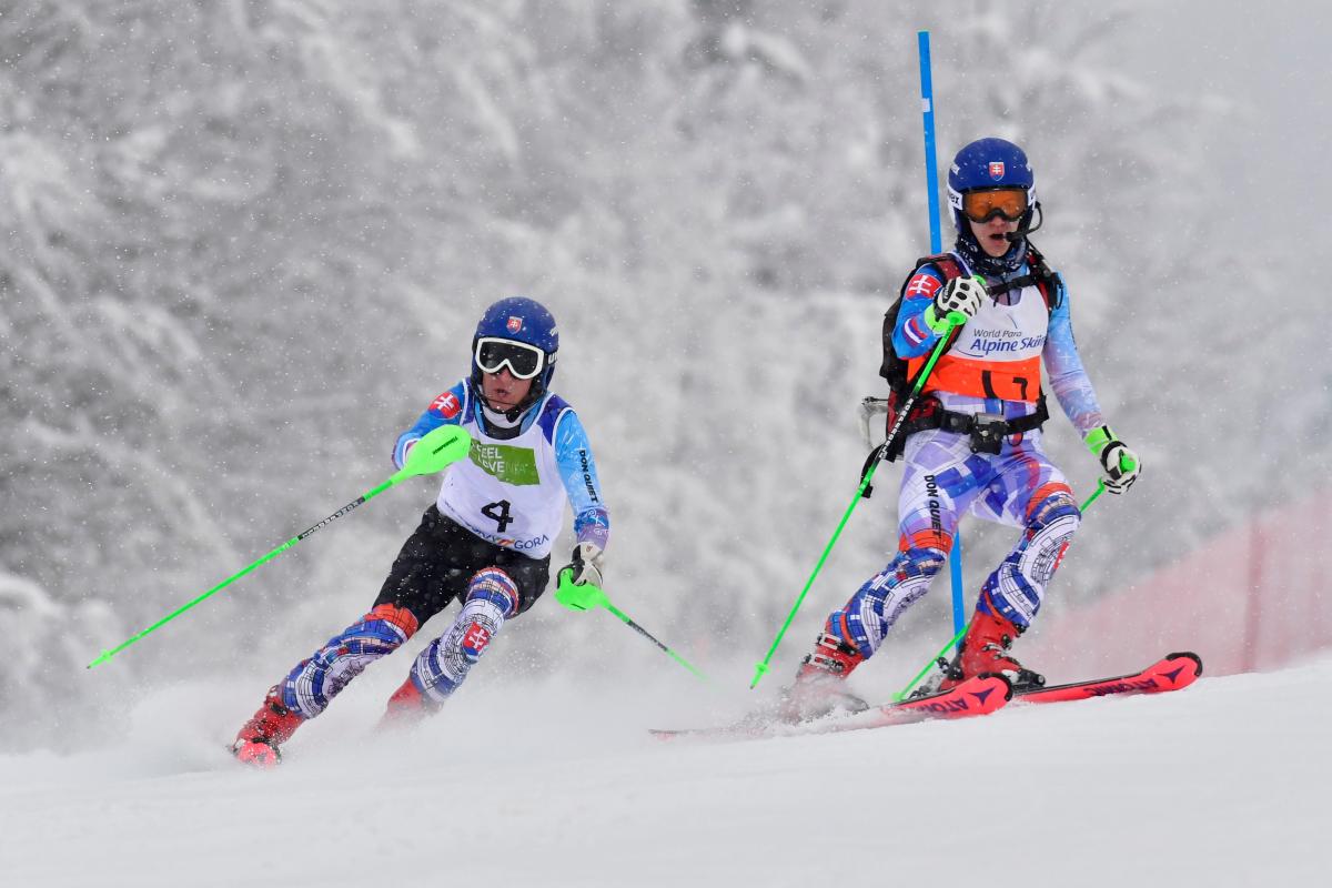 A female guide skier and a male blind alpine skier competing 