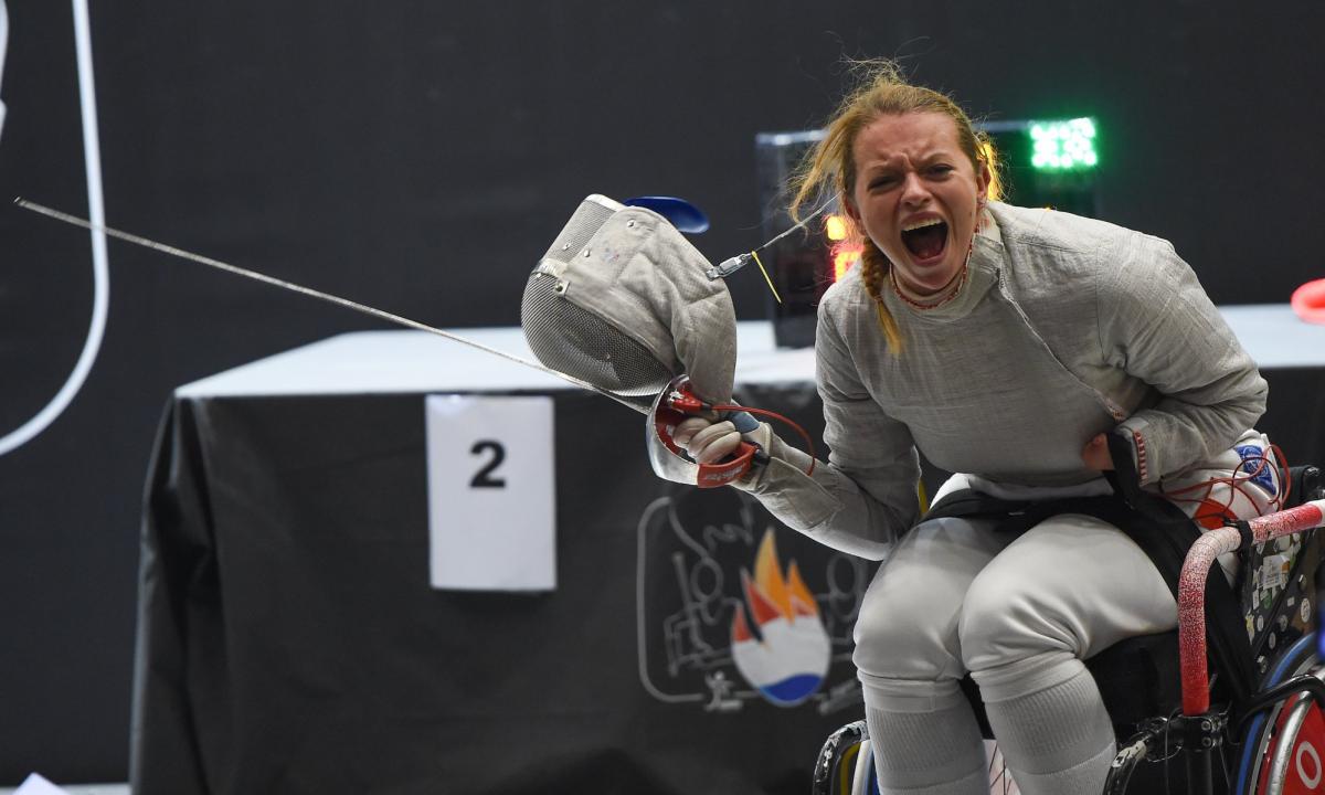 Female wheelchair fencer removes mask to celebrate