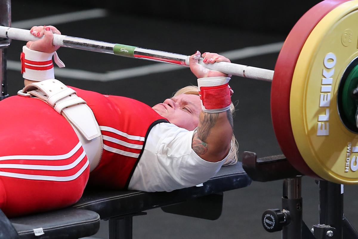 A female Para powerlifter with a red outfit preparing to lift the bar 