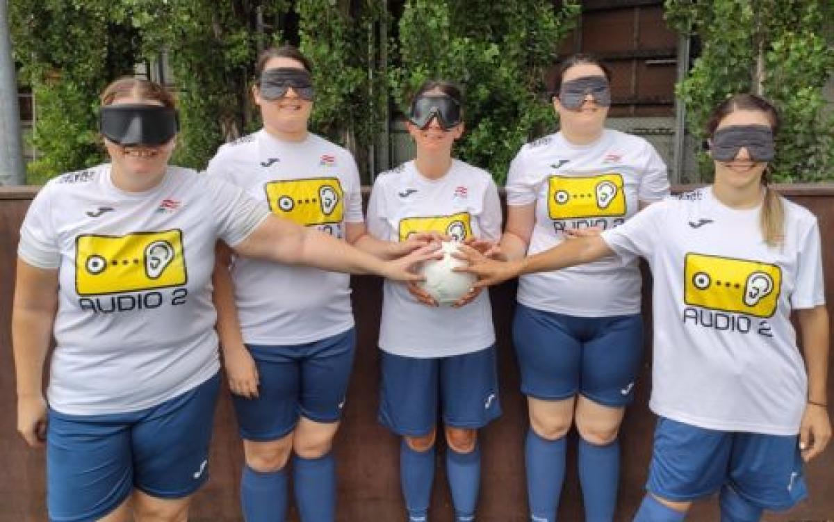 Five blind female footballer all holding a football together