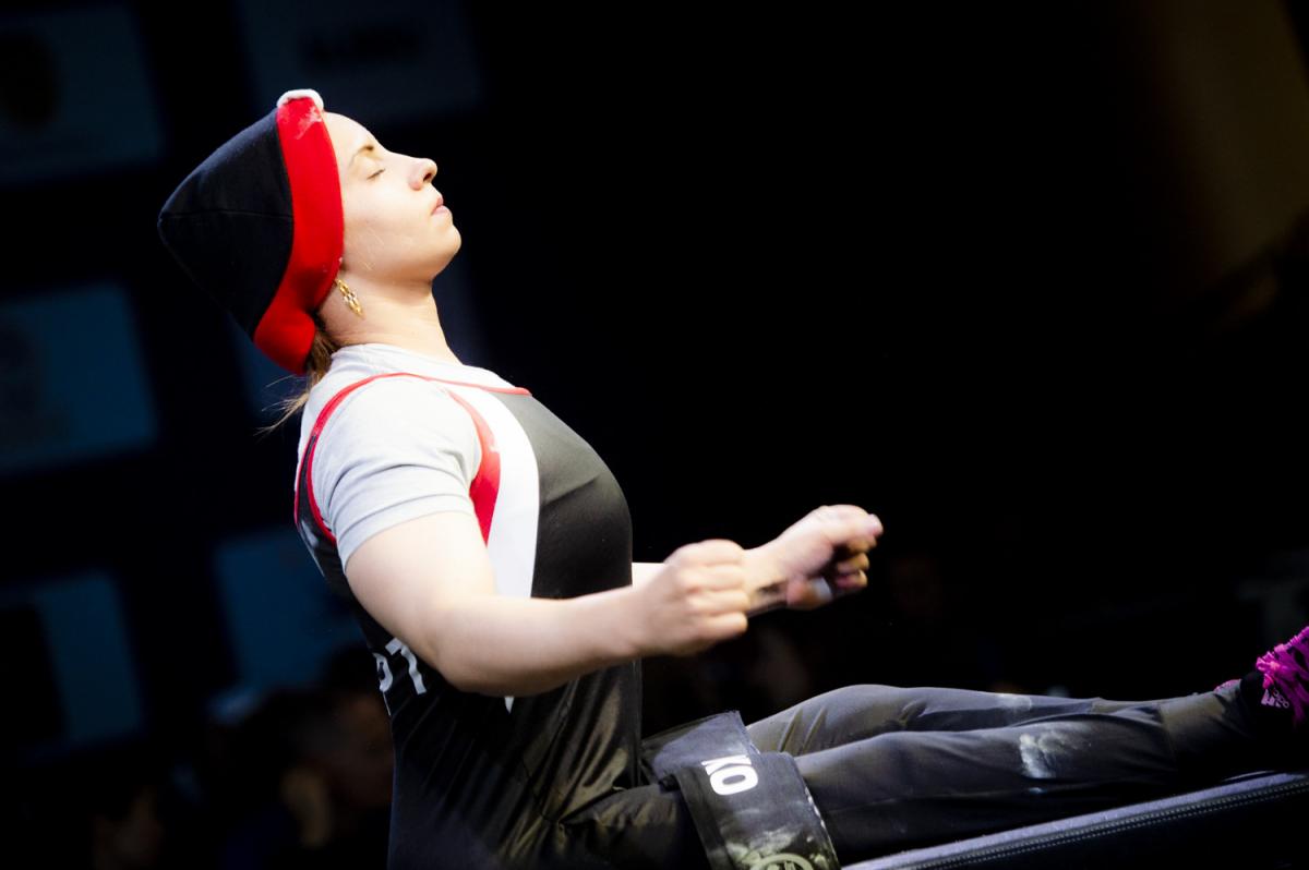 A woman with a black hood seated on a bench press 