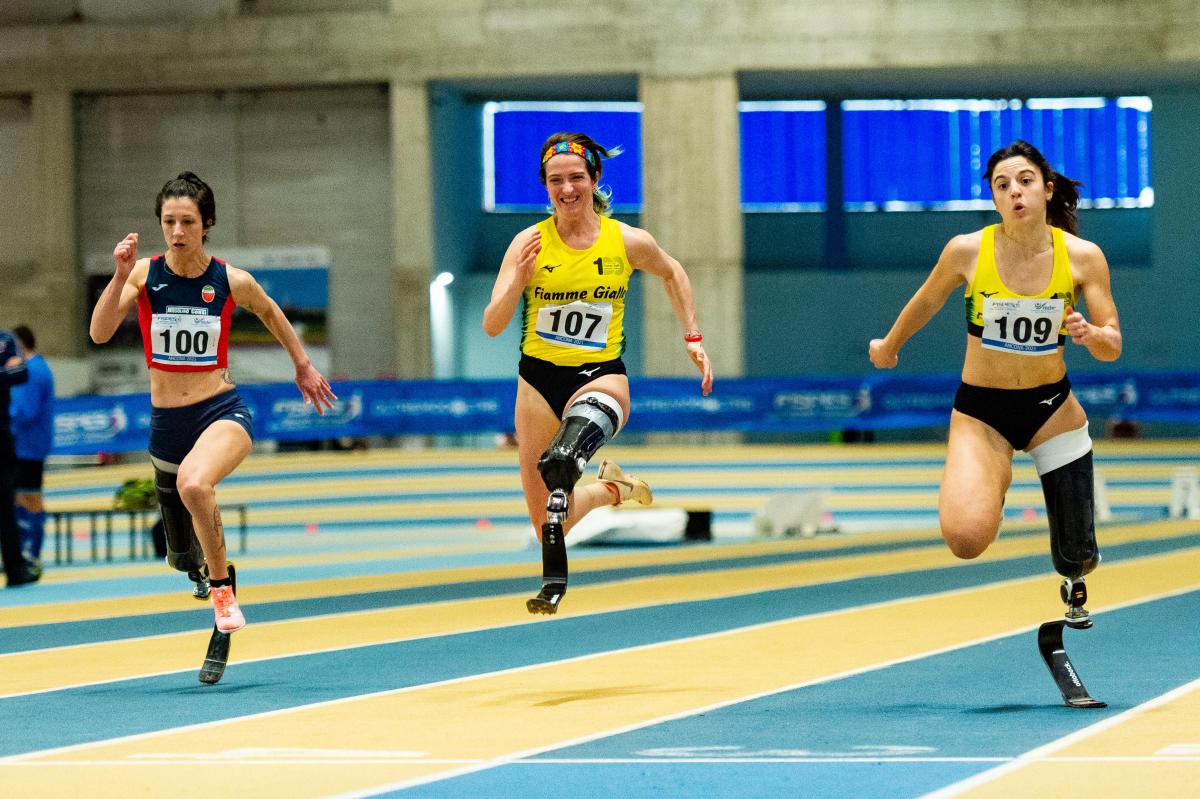 Three female blade runners in an indoor track