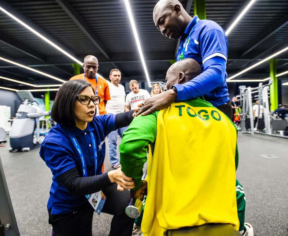 Woman helps train man how to lift weights