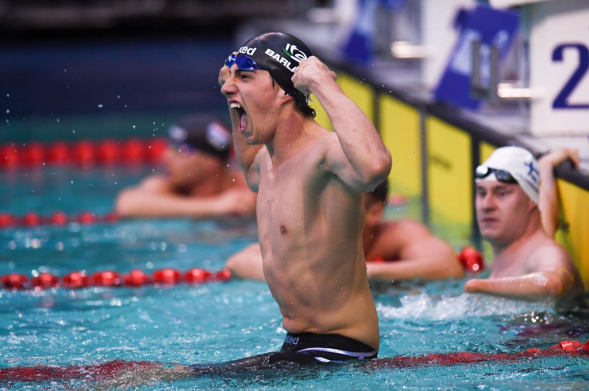 A swimmer celebrating in the pool observed by another swimmer