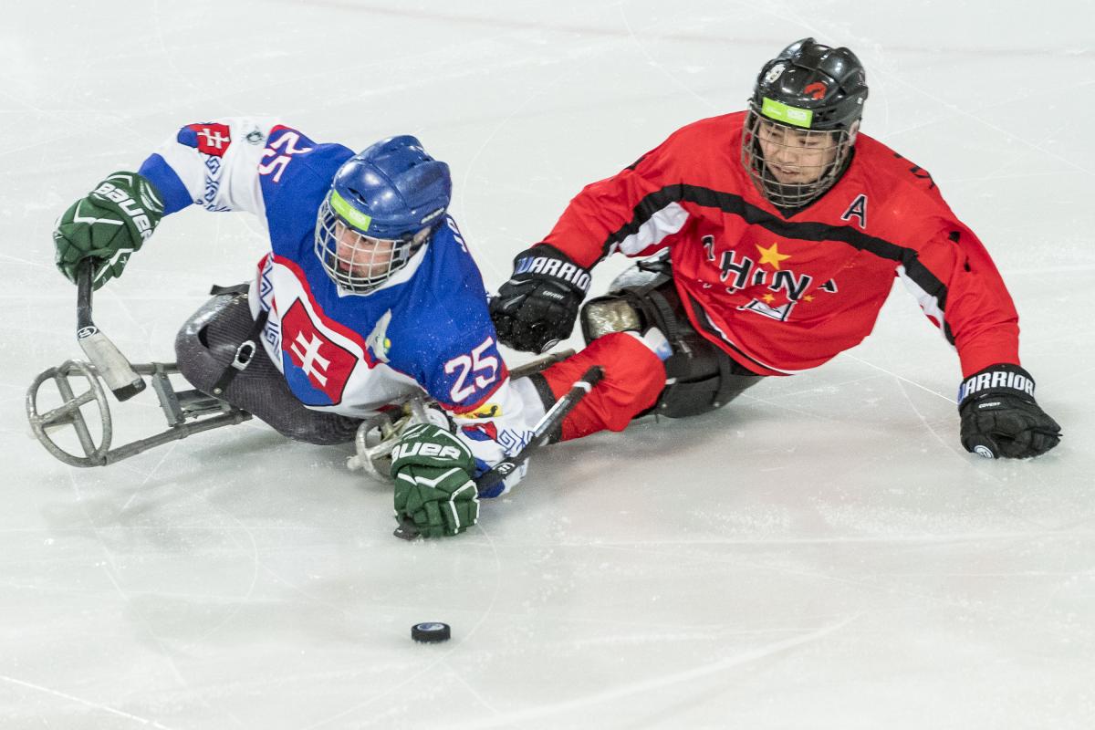 A Para ice hockey player with the uniform of Slovakia playing against another player from China