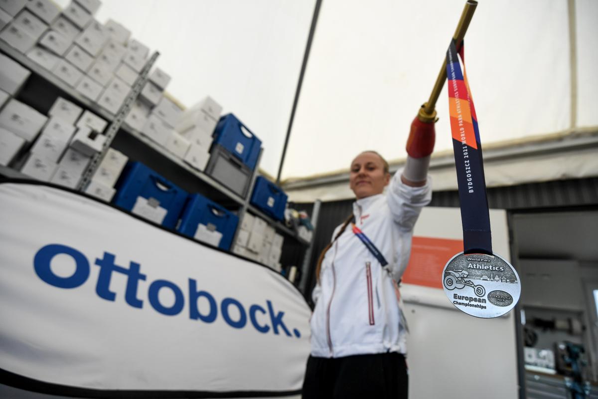 A woman with a prosthetic arm holding a silver medal