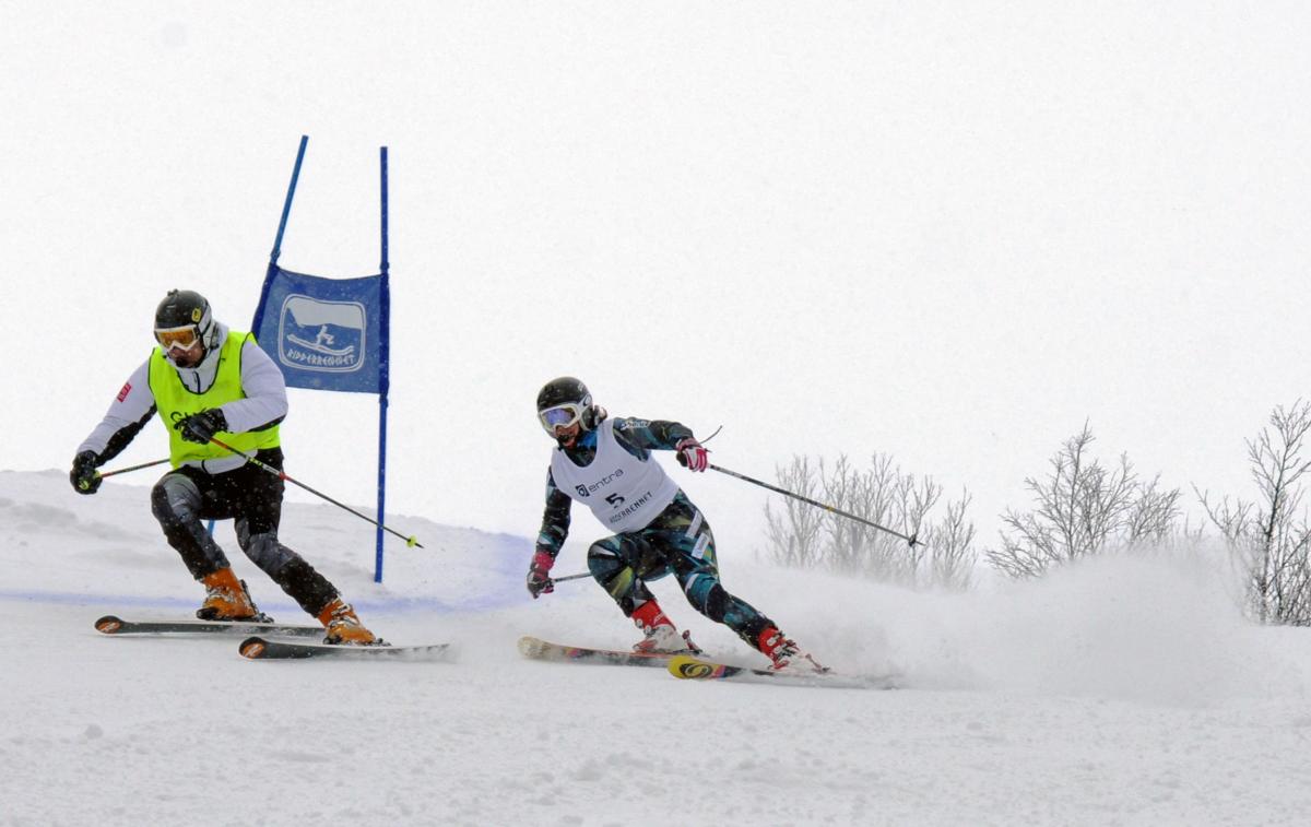 A female skier behind her guide in a Para alpine skiing competition