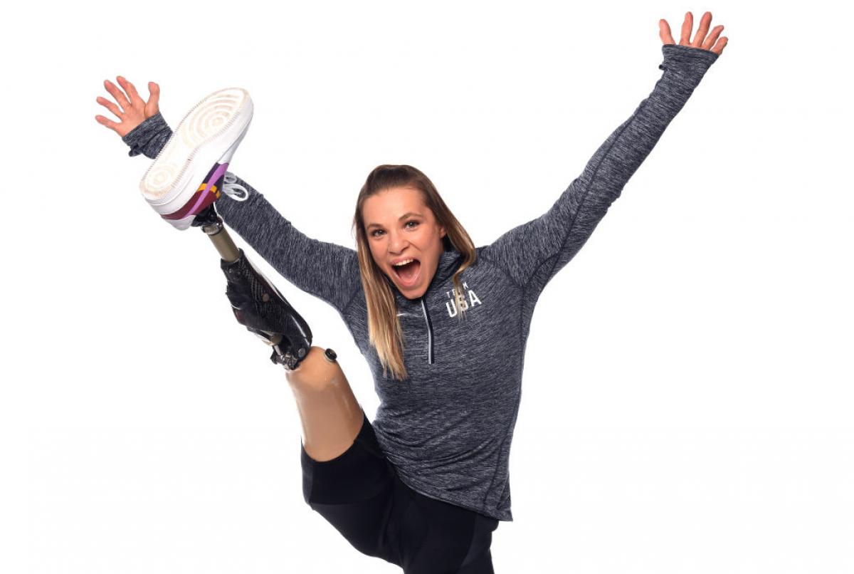 A woman stretching her prosthetic leg and smiling