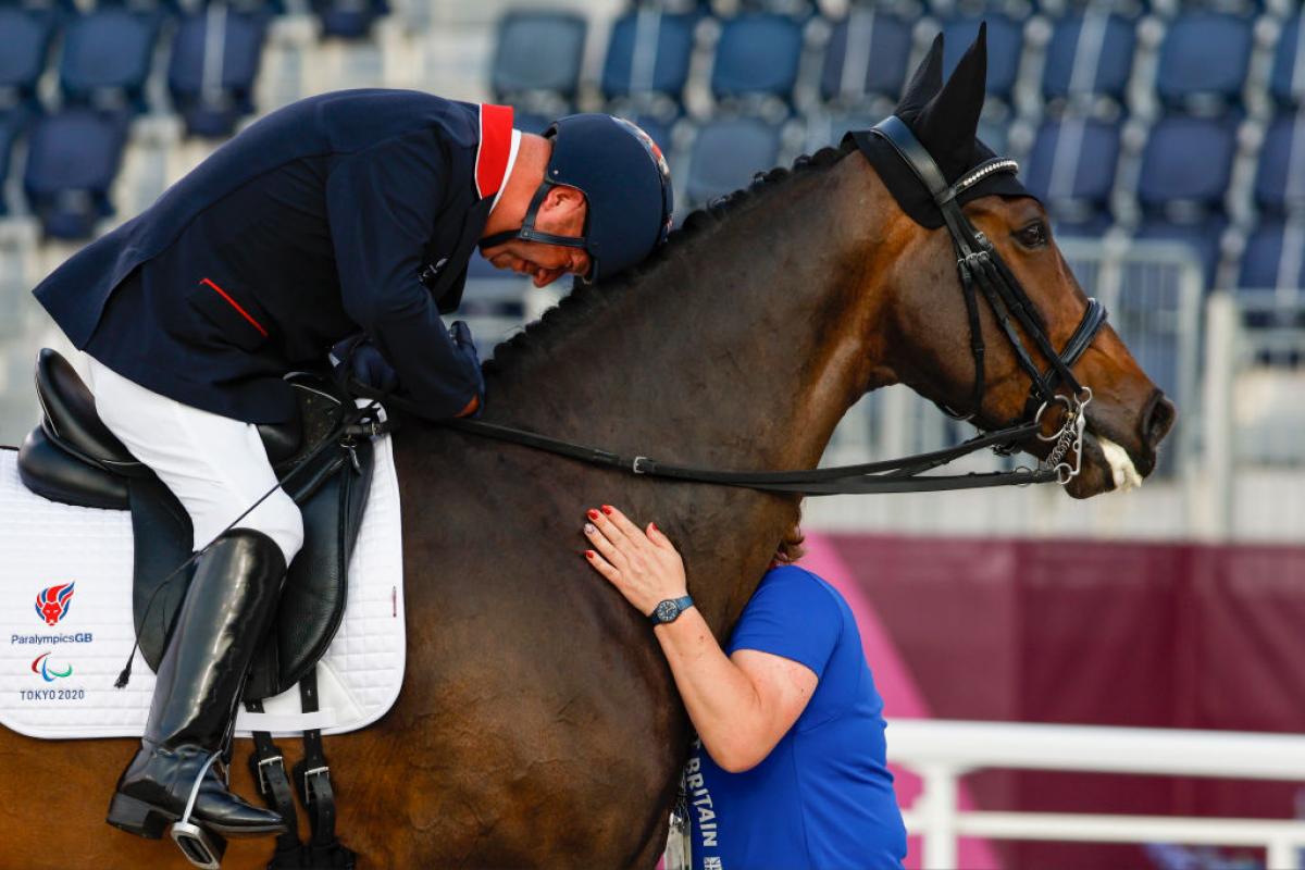 Lee Pearson lays his head on his horse