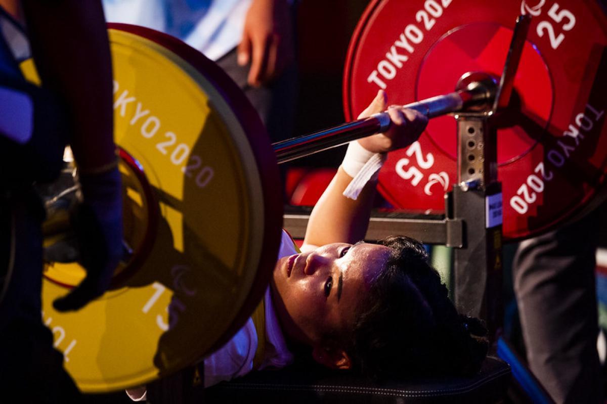 A woman on a bench press ready to lift a bar