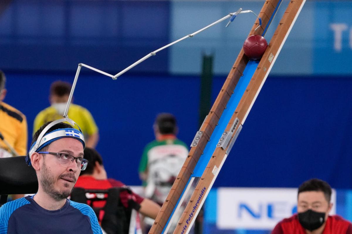 Boccia male athlete uses pointer to push ball