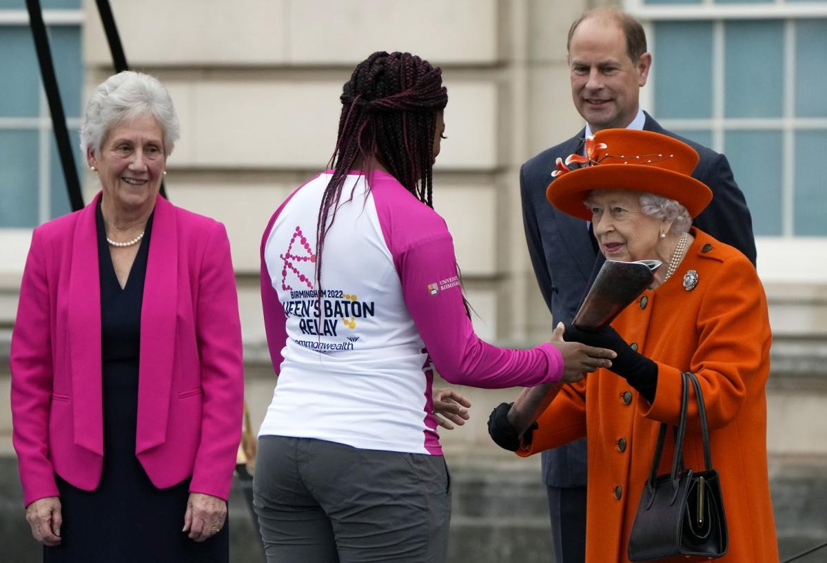 Queen Elizabeth II hands over the Queen's Baton to the first relay runner Kadeena Cox