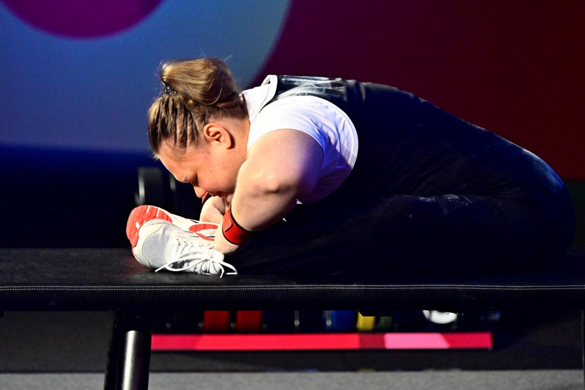 A female athlete stretching on the bench before her attempt.