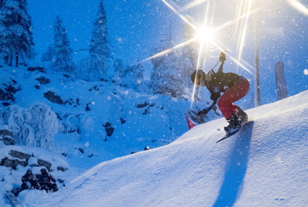 A female Para snowboarder riding on the snow with floodlights in the background