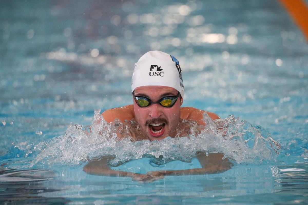 A man with a moustache swimming in the pool.