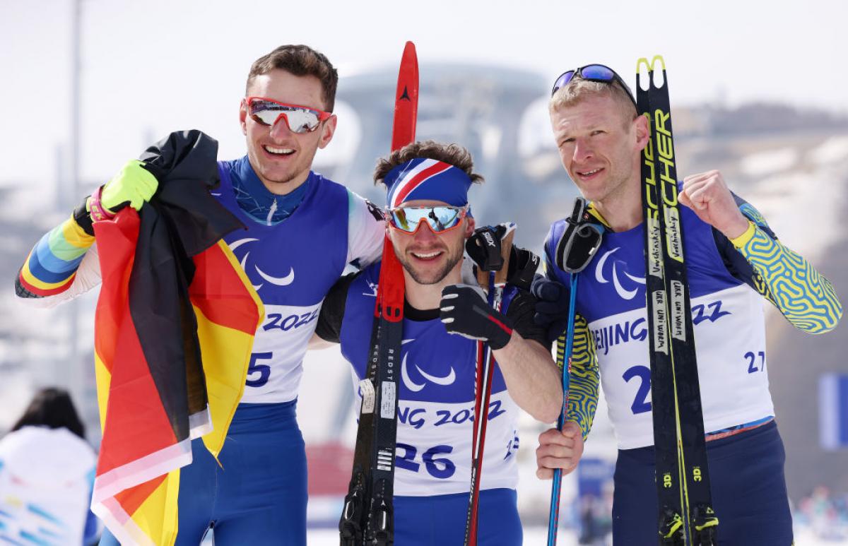 Gold medallist Benjamin Daviet of France (C), silver medallist Marco Maier of Germany (L) and bronze medallist Grygorii Vovchynskyi of Ukraine (R) celebrate their win in the Men's Sprint Free Technique Standing in the Beijing 2022 Paralympic Winter Games at Zhangjiakou National Biathlon Centre. 