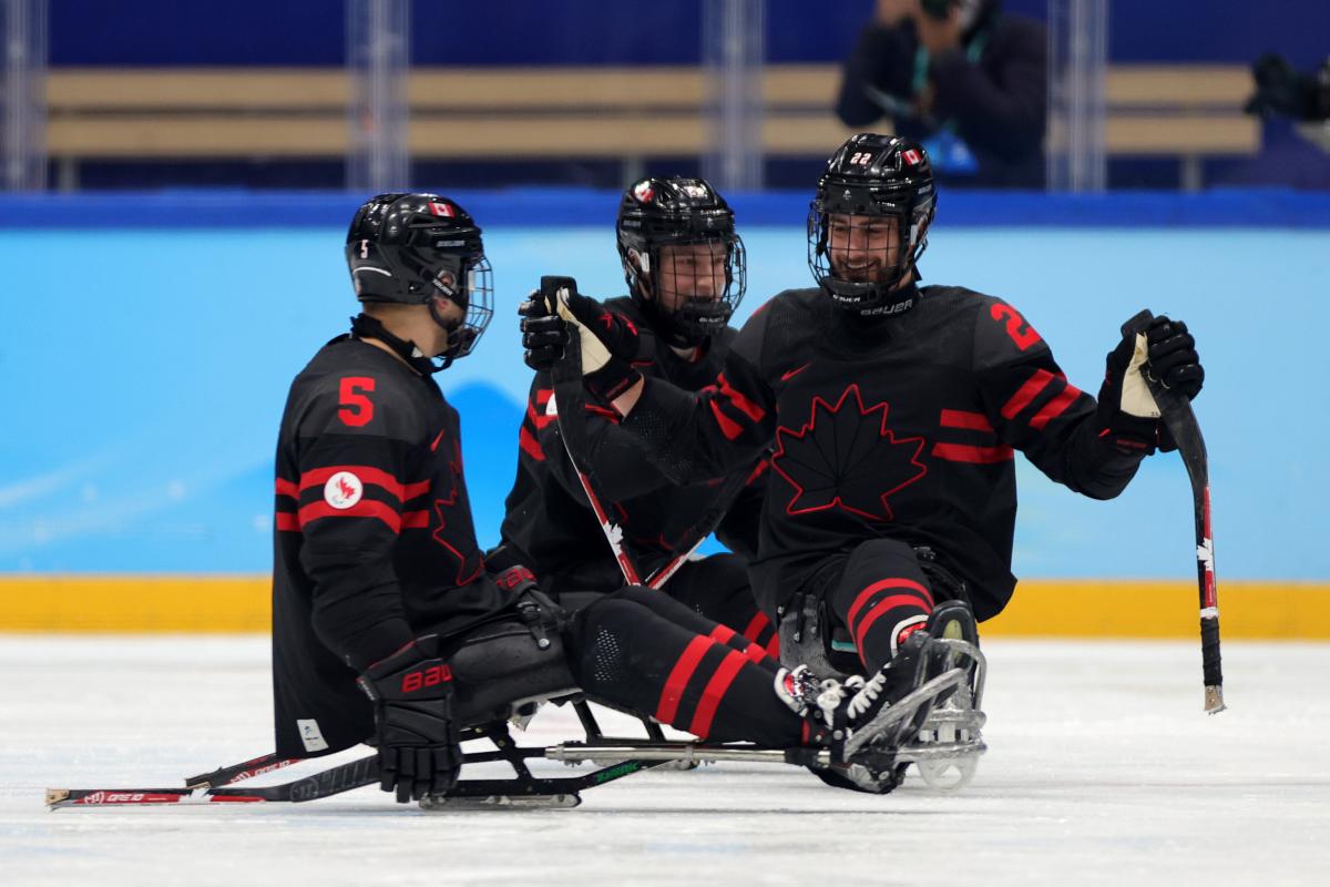 Three Para ice hockey players smiling to each other.