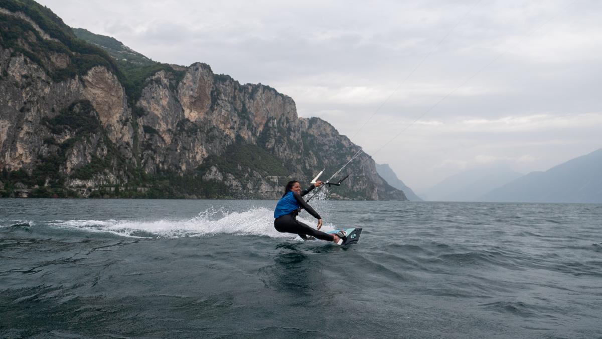 A female kiteboarder smiles as she makes her way across the water.